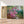 Charger l&#39;image dans la galerie, Première image de la peinture par numéro, Fleurs devant un Ruisseau , dans un cadre en bois sur du parquet.
