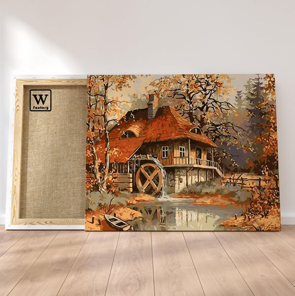 Première image de la peinture par numéro, Maison au Moulin , dans un cadre en bois sur du parquet.