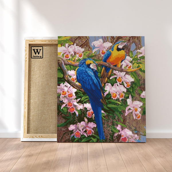 Première image de la peinture par numéro, Perroquets et Fleurs Exotiques , dans un cadre en bois sur du parquet.